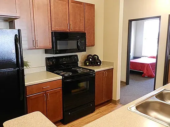 A kitchen with a stove , refrigerator , microwave and sink.