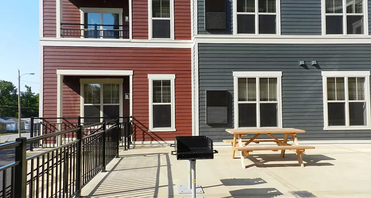 A red and gray building with a picnic table in front of it.