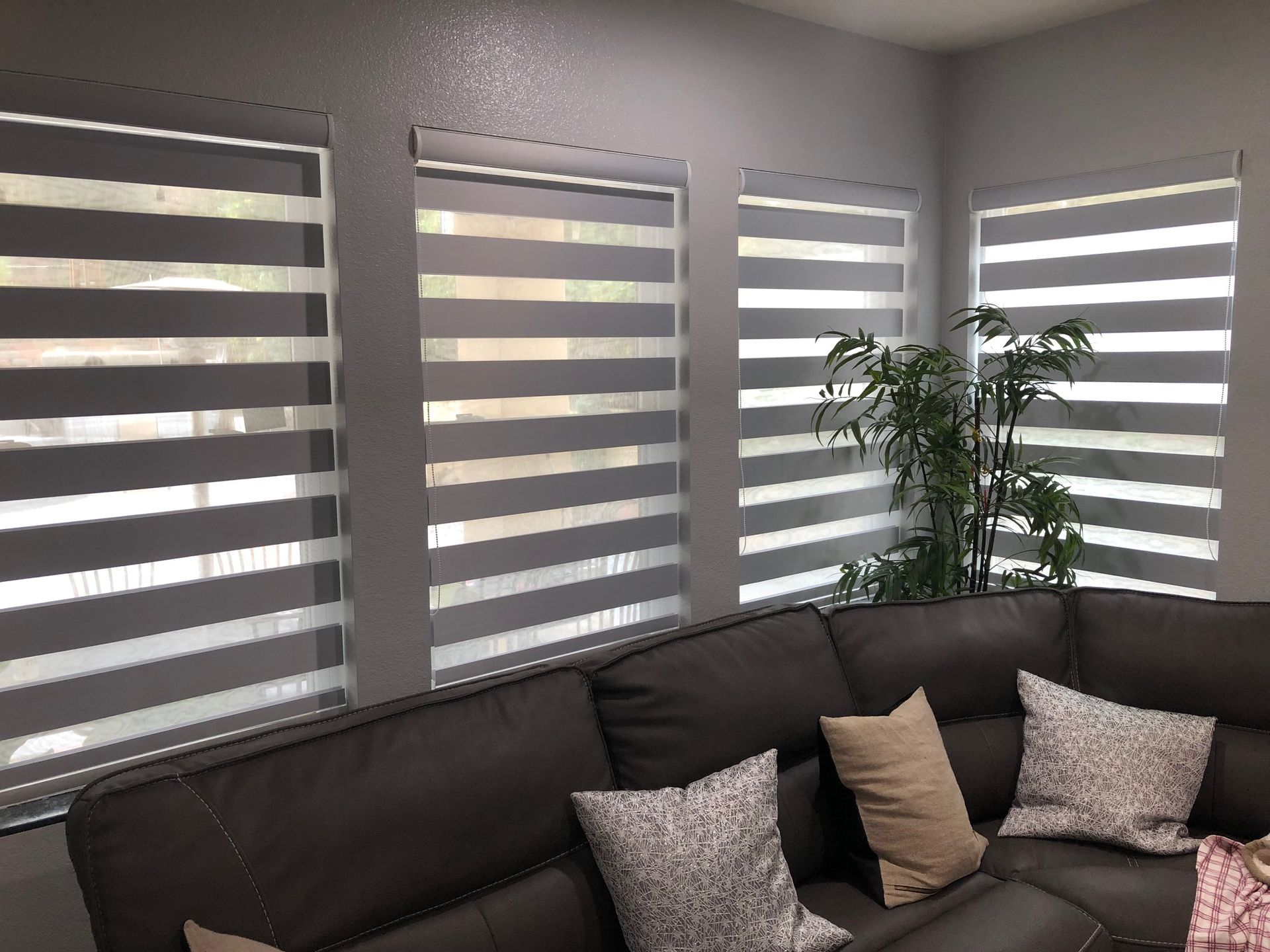 A living room with a couch and striped blinds on the windows.