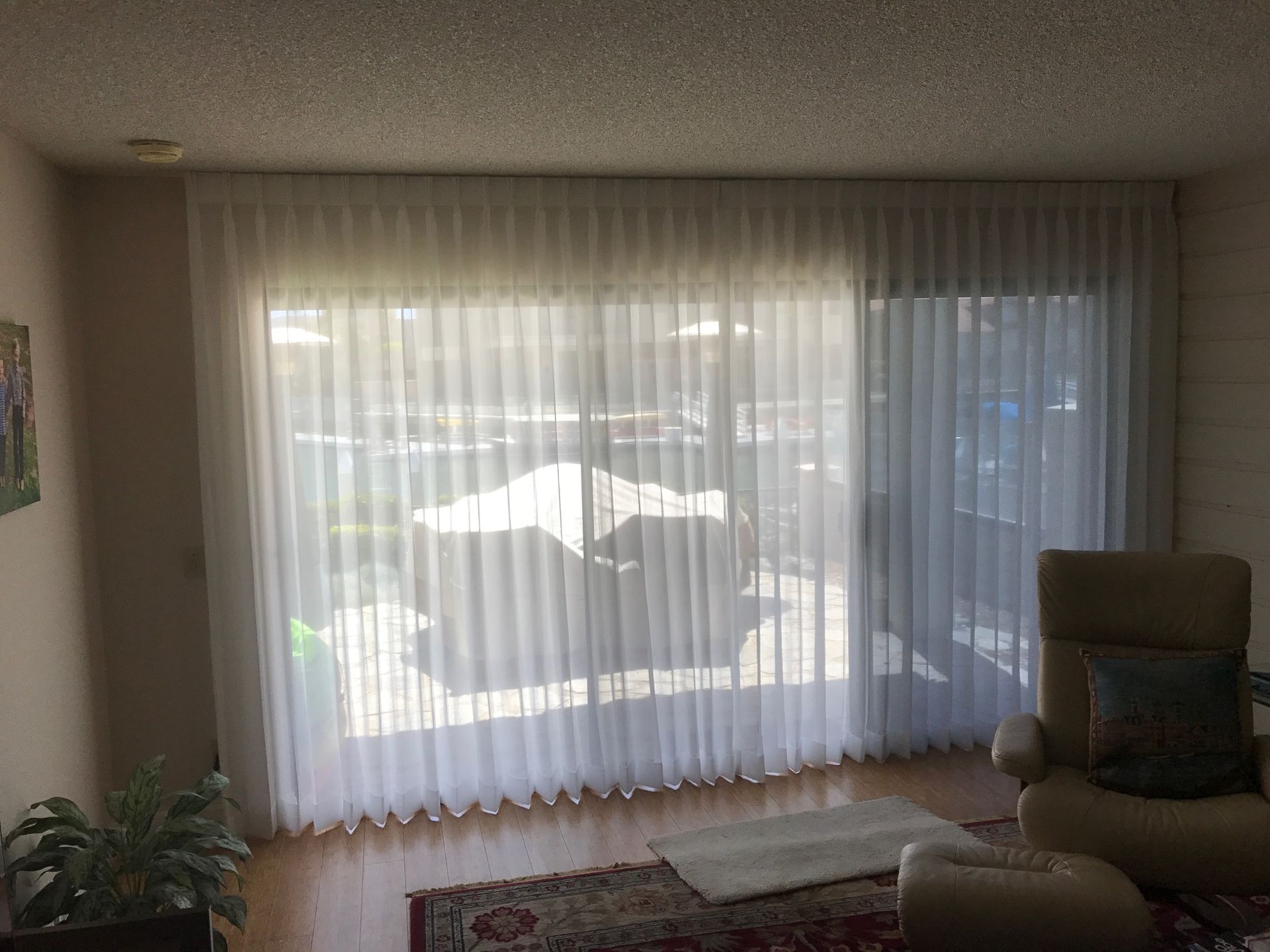 A living room with a sliding glass door and white curtains.