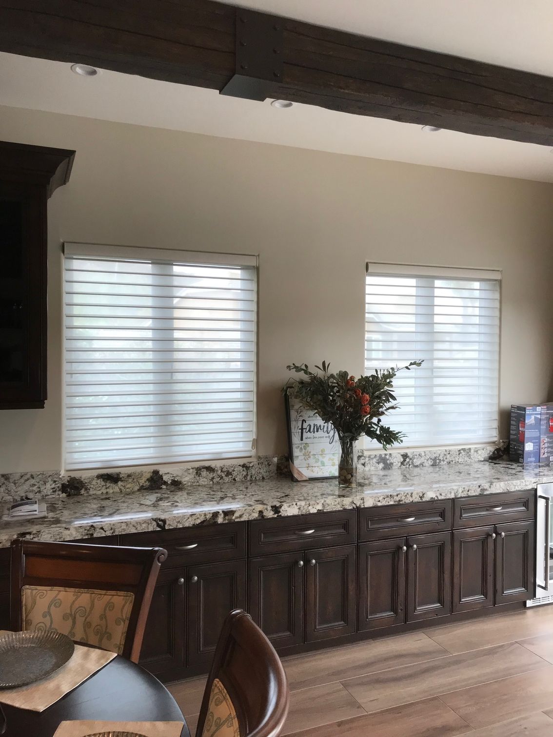 A kitchen with a table and chairs and a vase of flowers on the counter.