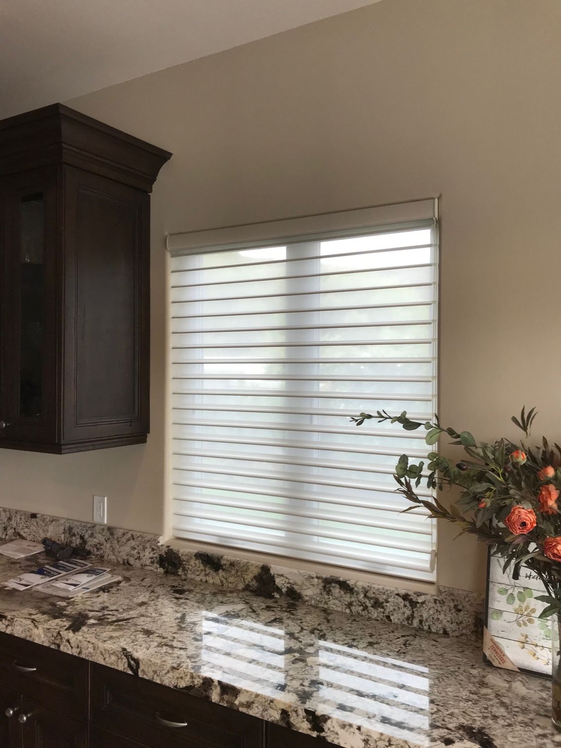 A kitchen with granite counter tops and a window with blinds.