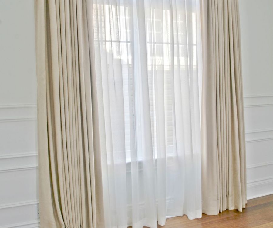 A pair of white curtains are hanging on a window in a room.