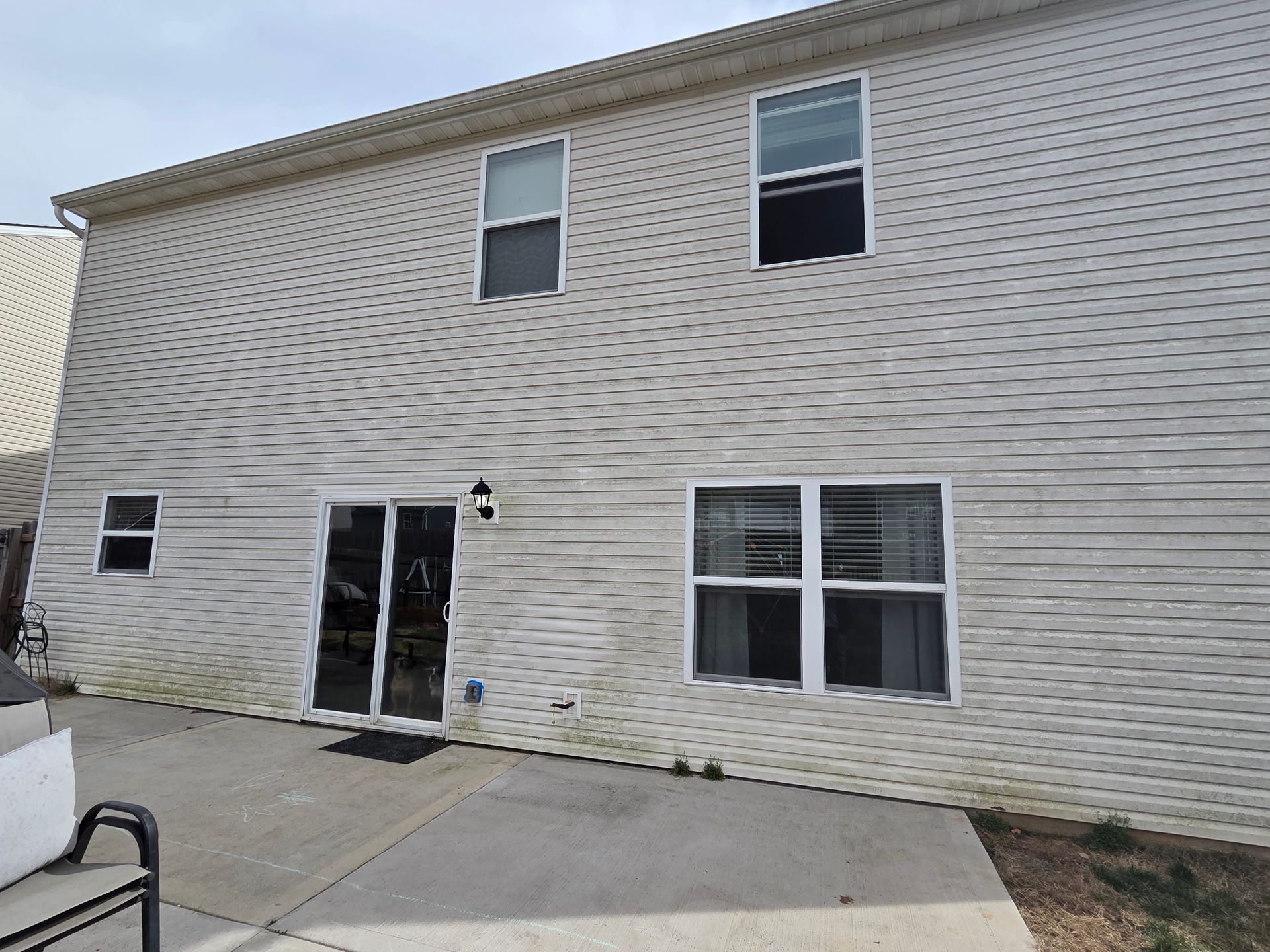 The back of a house with a lot of windows and a sliding glass door.