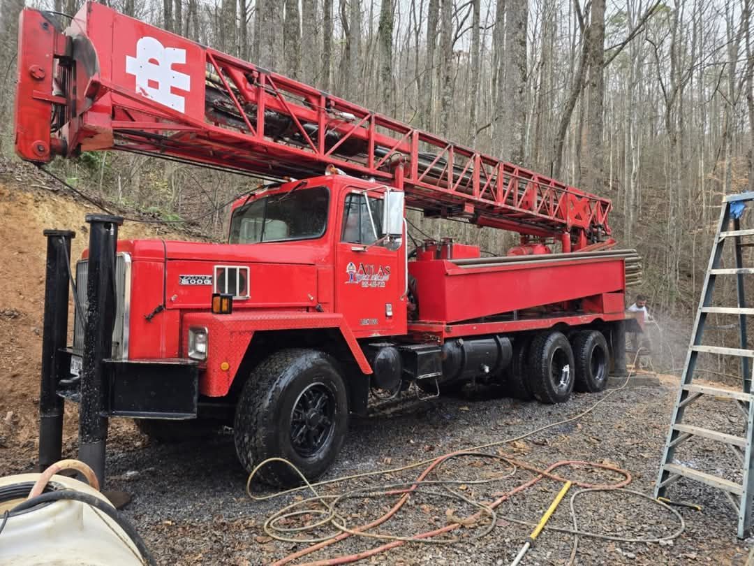 A man is washing a truck with a high pressure washer.