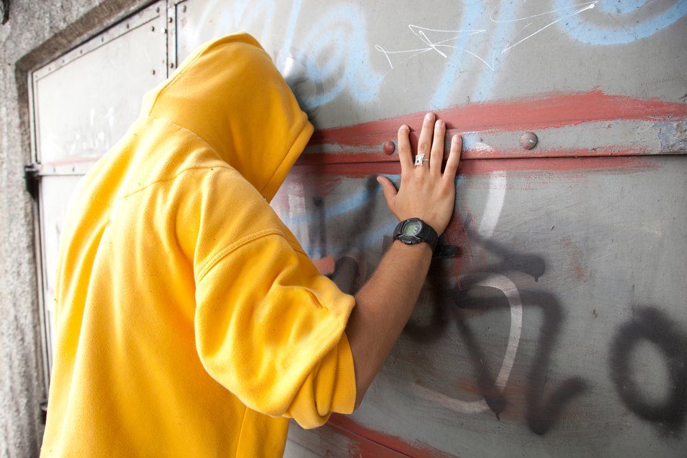 Man In Hoodie Facing Wall With Graffiti — Criminal Law Firm In Brisbane, QLD