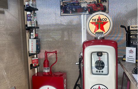 A vintage red and white Texaco gas pump, a matching oil drum with a hand pump, and shelves of supplies in a garage space. | Waggener Brake and Auto Repair