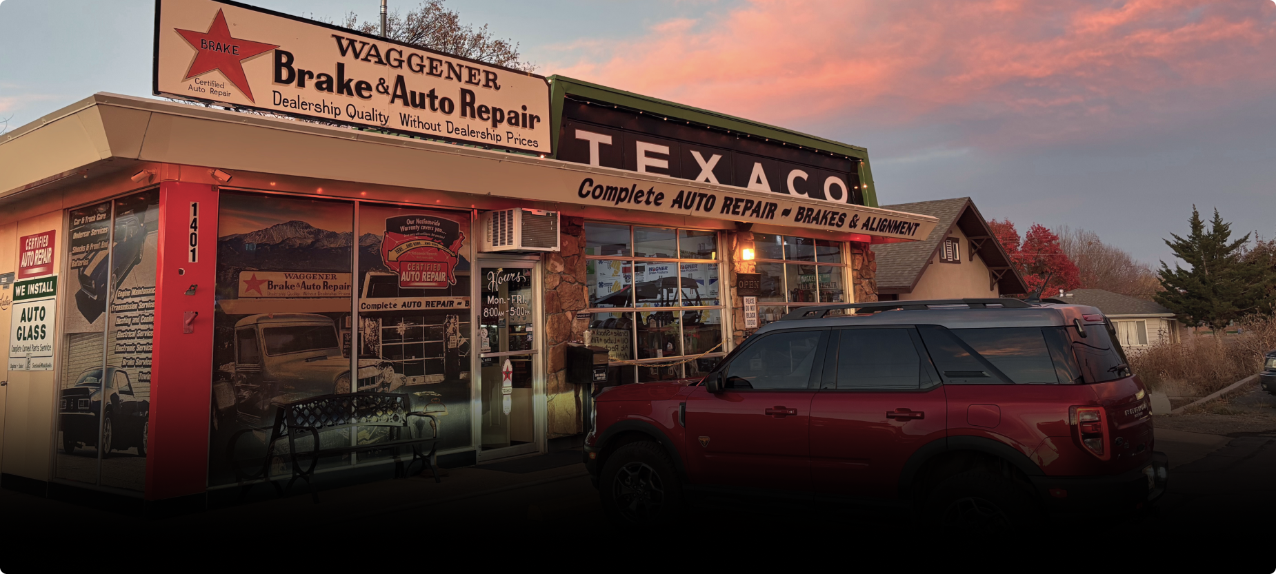 A red SUV parked in front of a Waukesha Brake & Auto Repair shop with a vintage Texaco sign at sunset. | Waggener Brake and Auto Repair