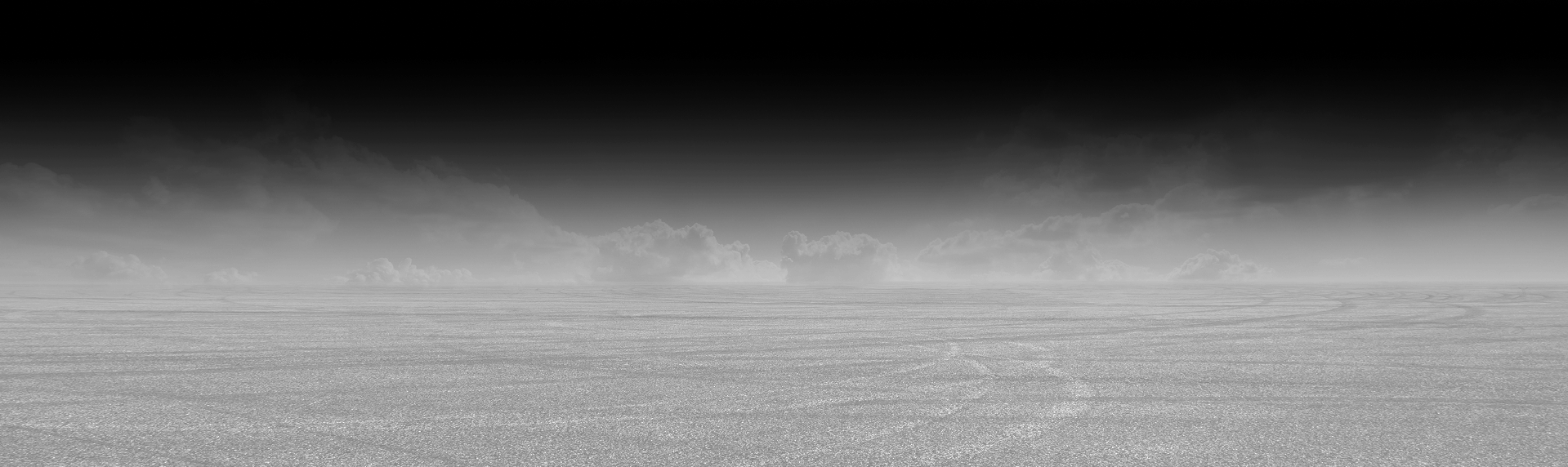 A black and white, low-angle landscape featuring a vast, flat, textured terrain transitioning into a misty horizon. | Waggener Brake and Auto Repair