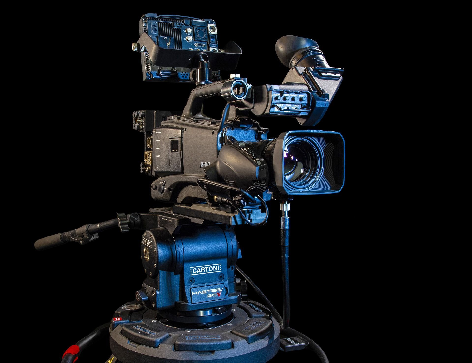 A video camera is sitting on top of a stand on a black background.