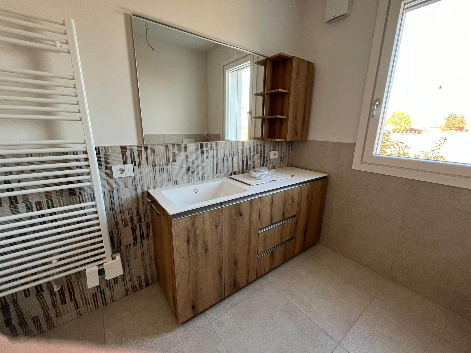 Un bagno con lavandino, specchio e portasciugamani.