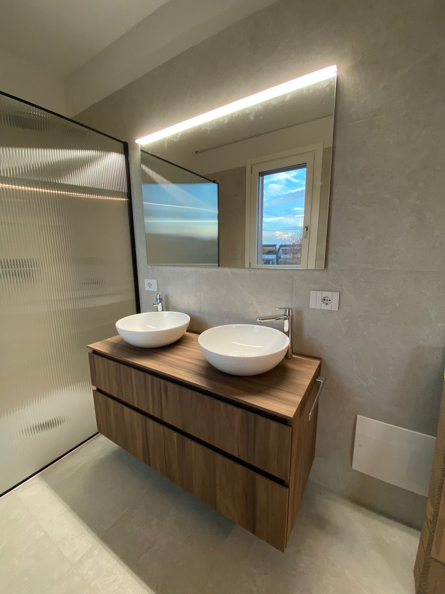 Un bagno con due lavandini, uno specchio e una finestra.