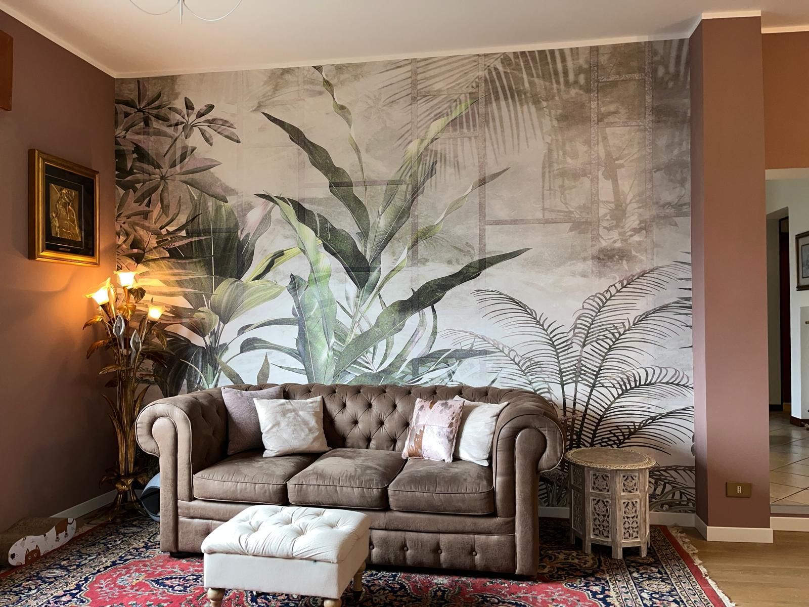 Un soggiorno con un divano, un pouf e un grande murale sulla parete.