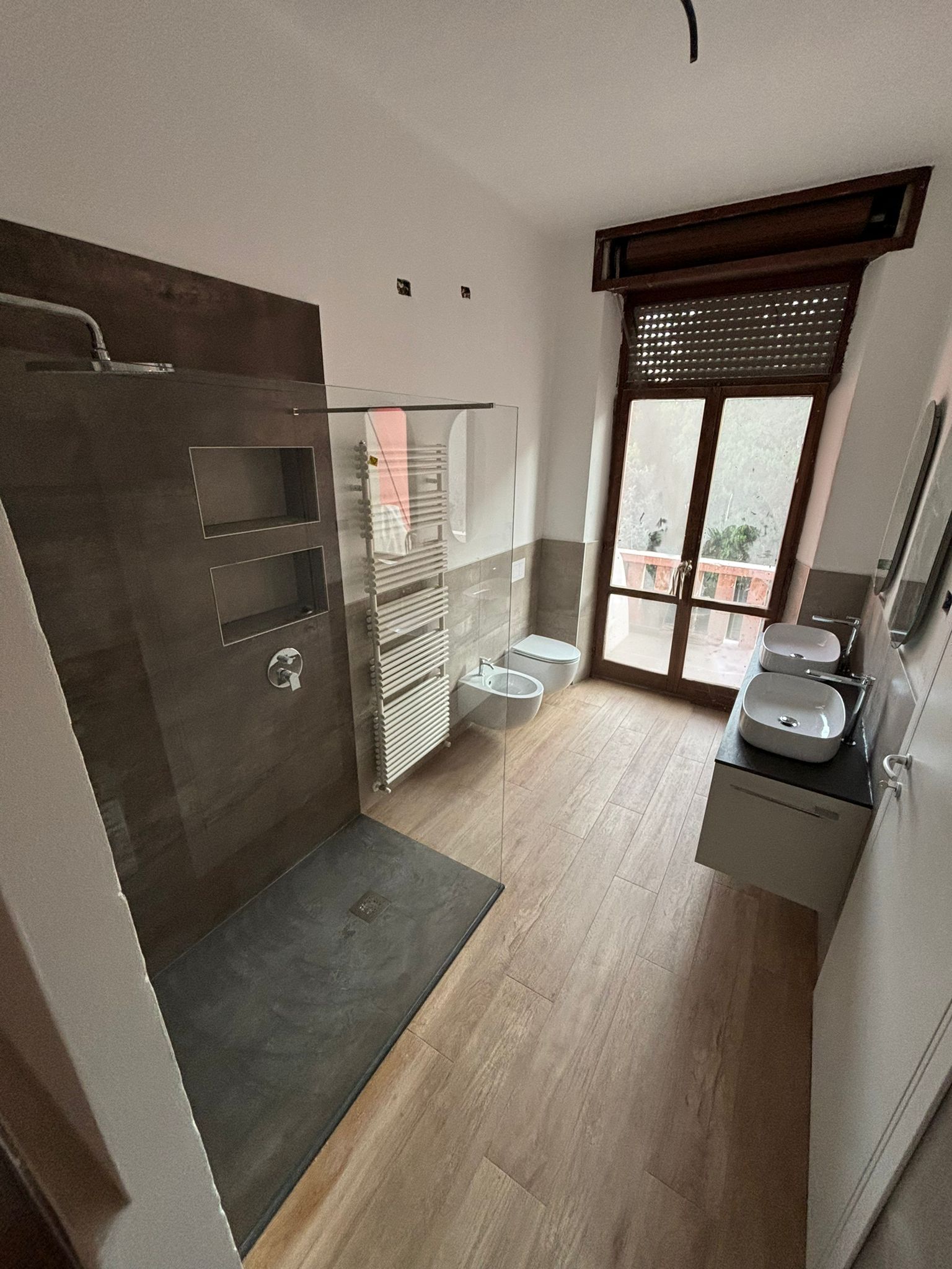 Un bagno con cabina doccia e due lavandini.