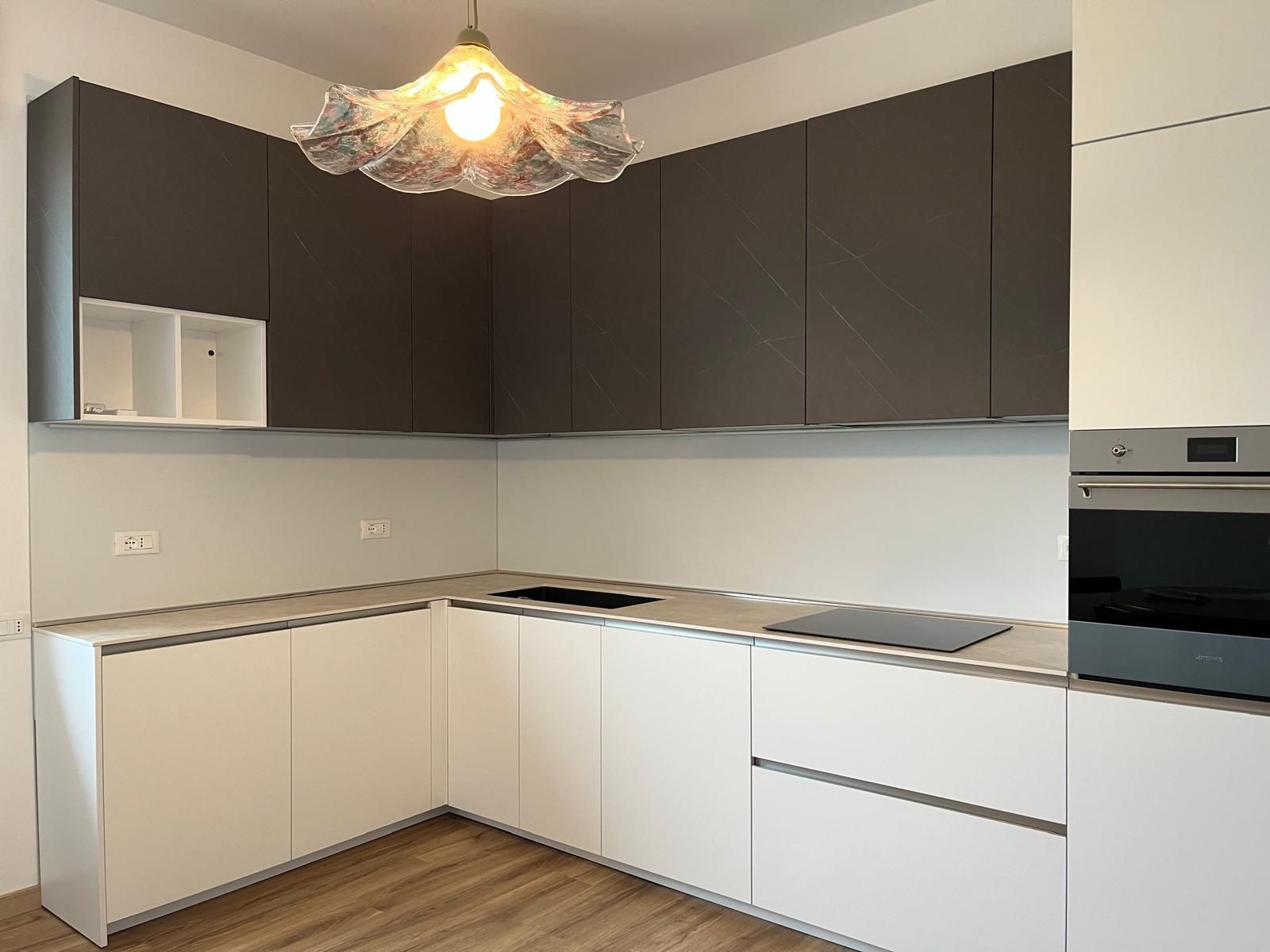 Una cucina con mobili bianchi e un forno con piano cottura in acciaio inossidabile.