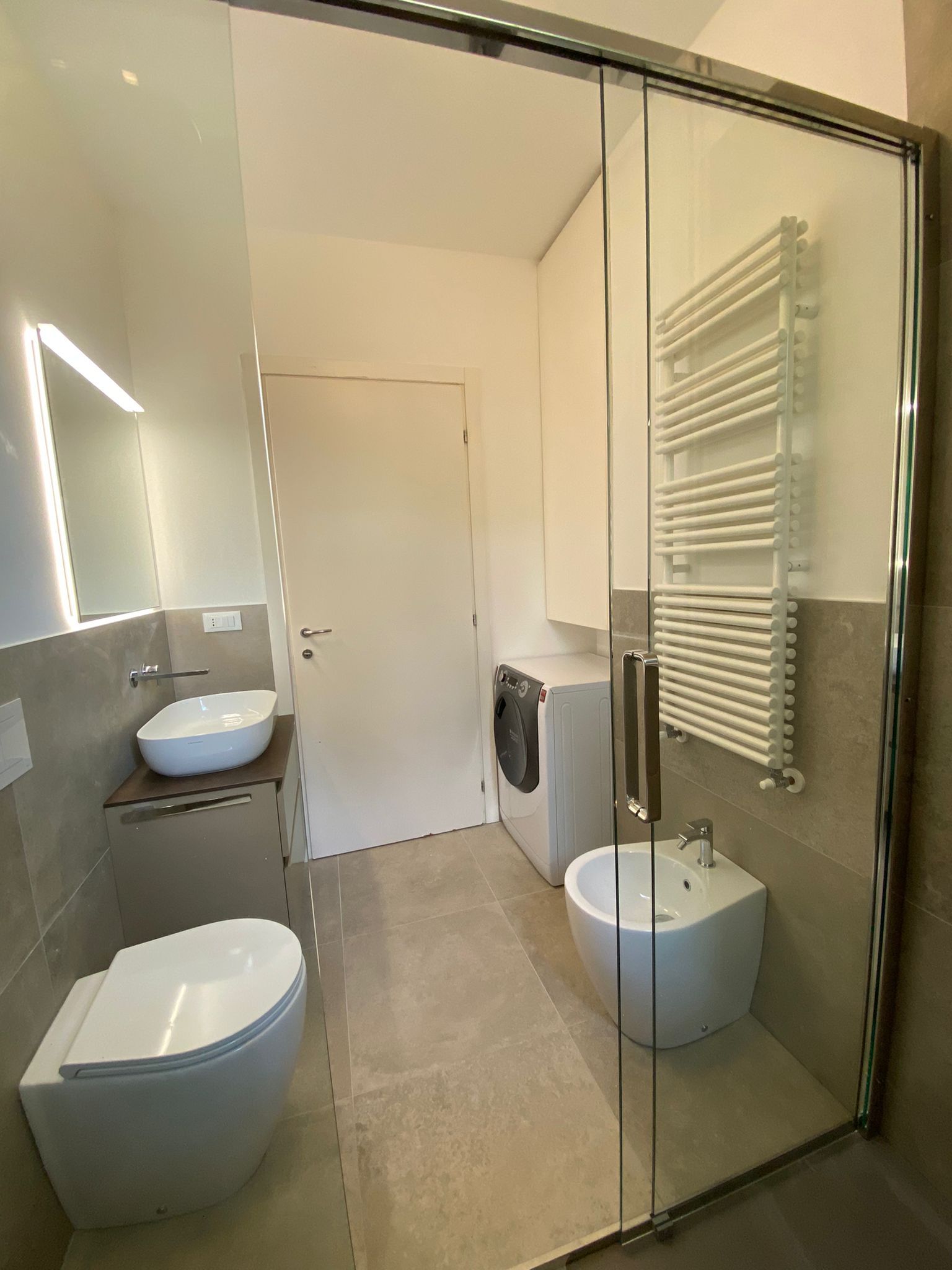 Un bagno con due water, un bidet, un lavandino e uno specchio.