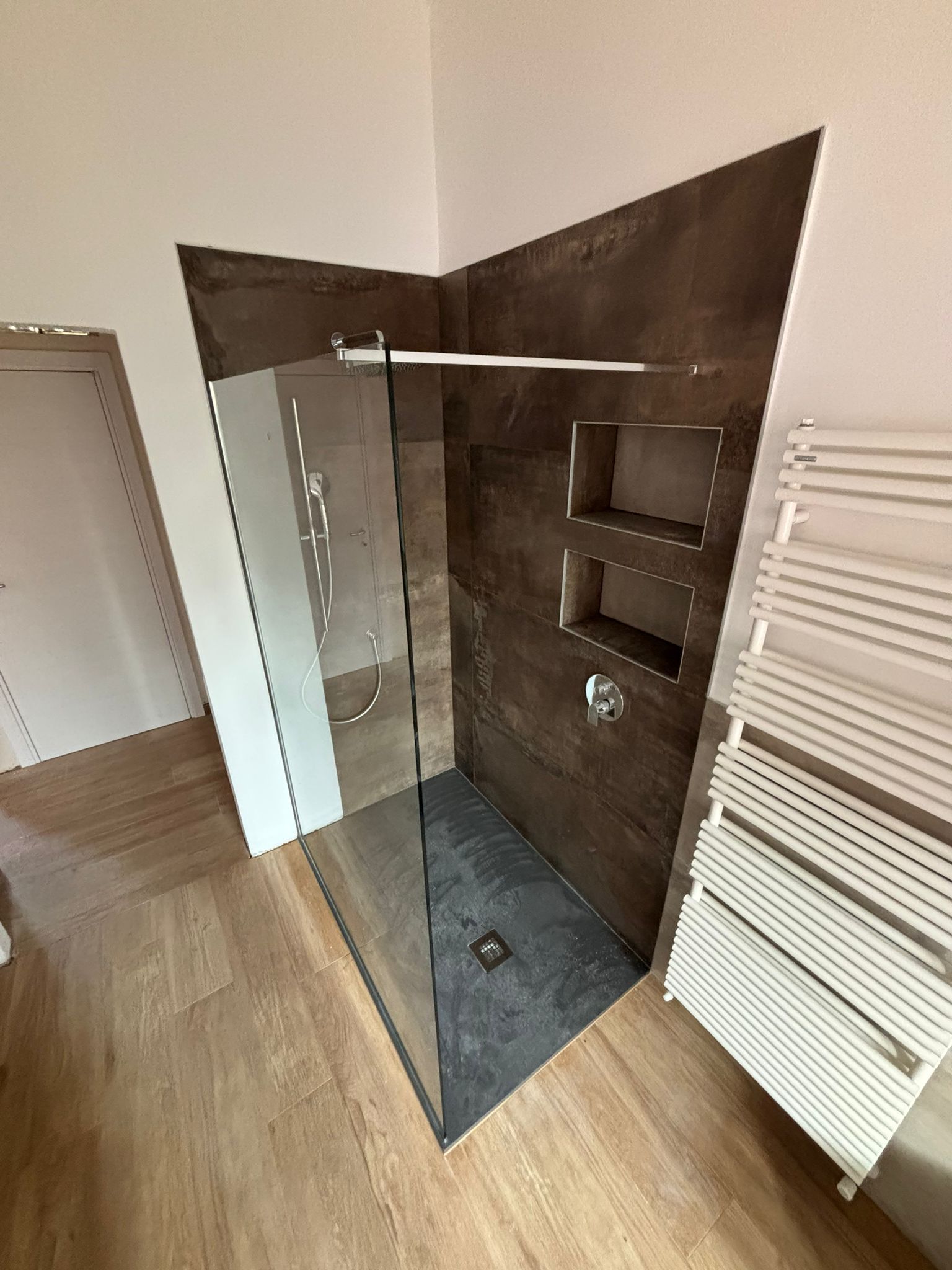 Un bagno con cabina doccia e portasciugamani.