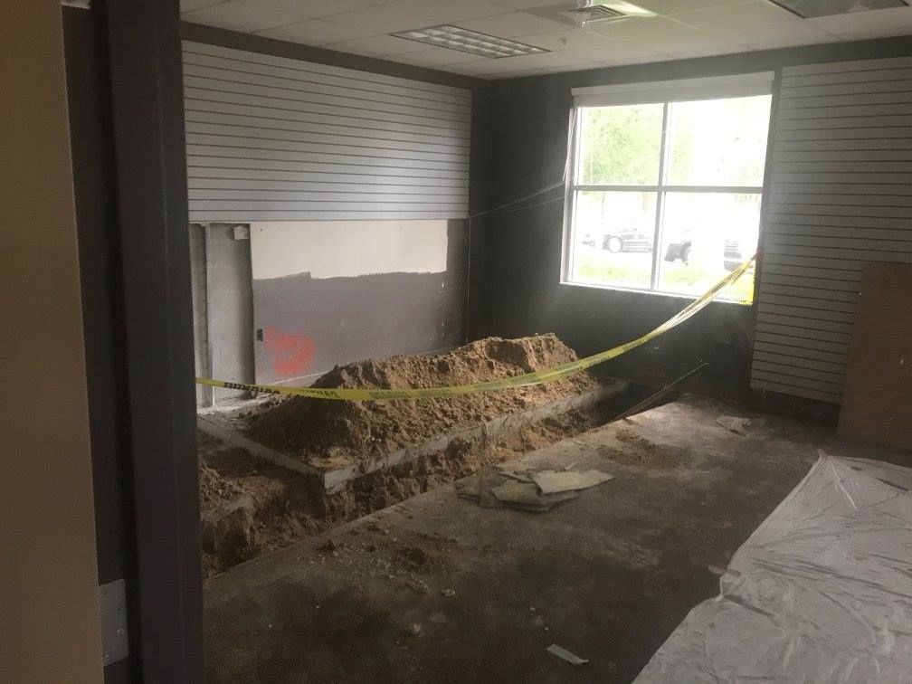 Room under renovation. Dirt pile in the middle, yellow caution tape. Window visible on right.