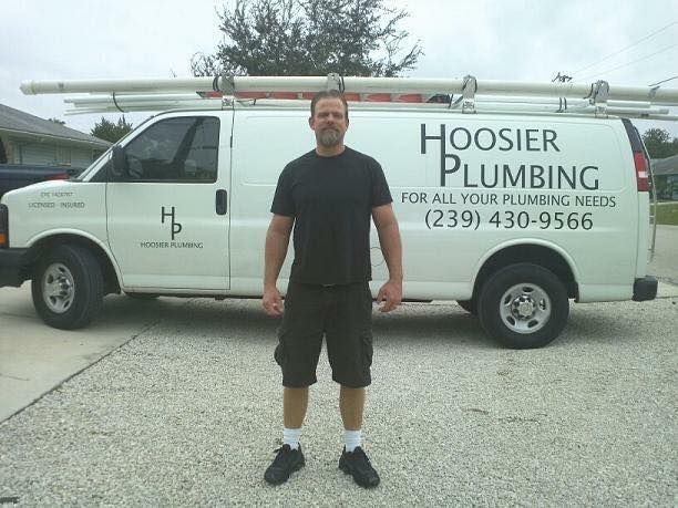 Man in front of a Hoosier Plumbing van. The van is white, with plumbing supplies on top.