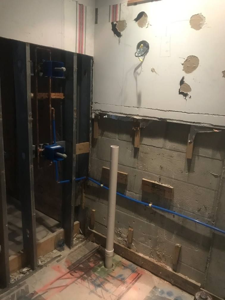 Bathroom under construction with exposed plumbing, framing, and unfinished walls.