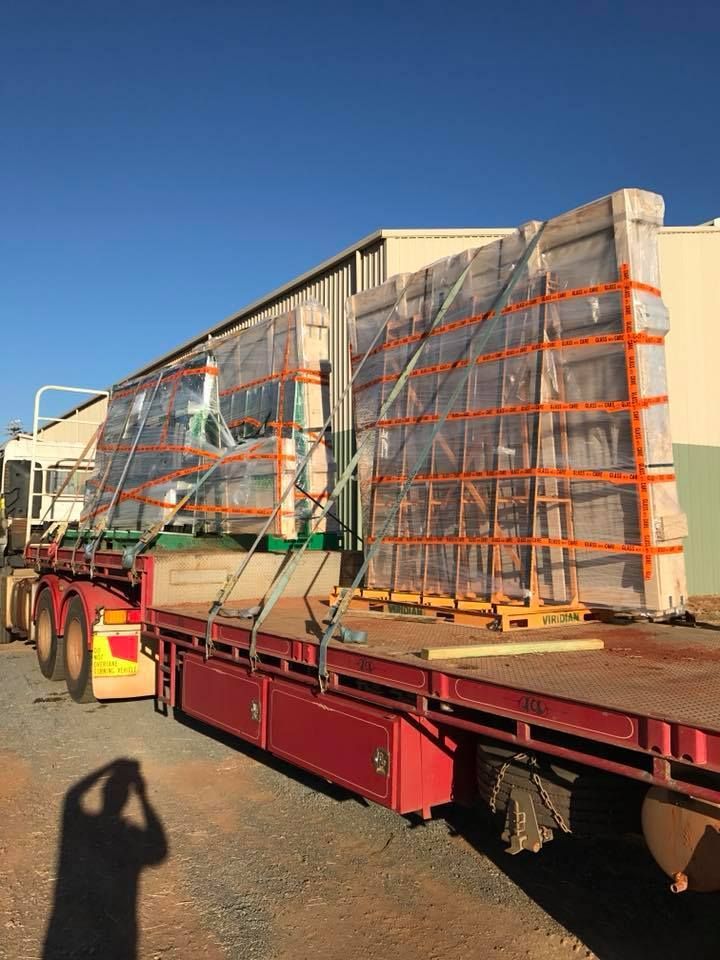 A Red Semi Truck Is Carrying A Large Piece Of Glass — GGS Alice Glass & Aluminium In Ciccone, NT
