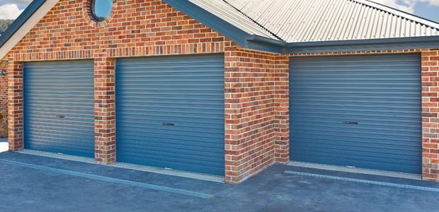 Three Blue Garage Doors Are On A Brick Building — GGS Alice Glass & Aluminium In Ciccone, NT