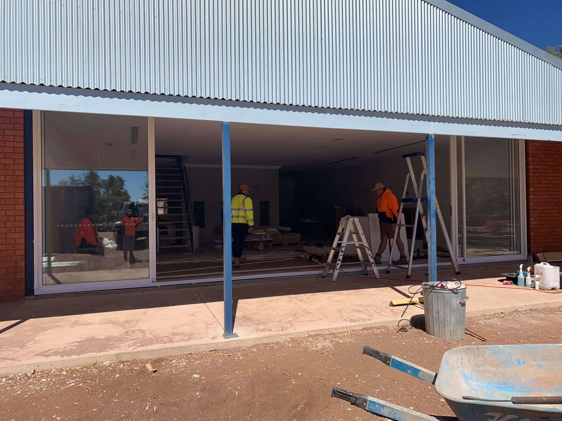 A Group Of Construction Workers Are Working On A Building — GGS Alice Glass & Aluminium In Ciccone, NT