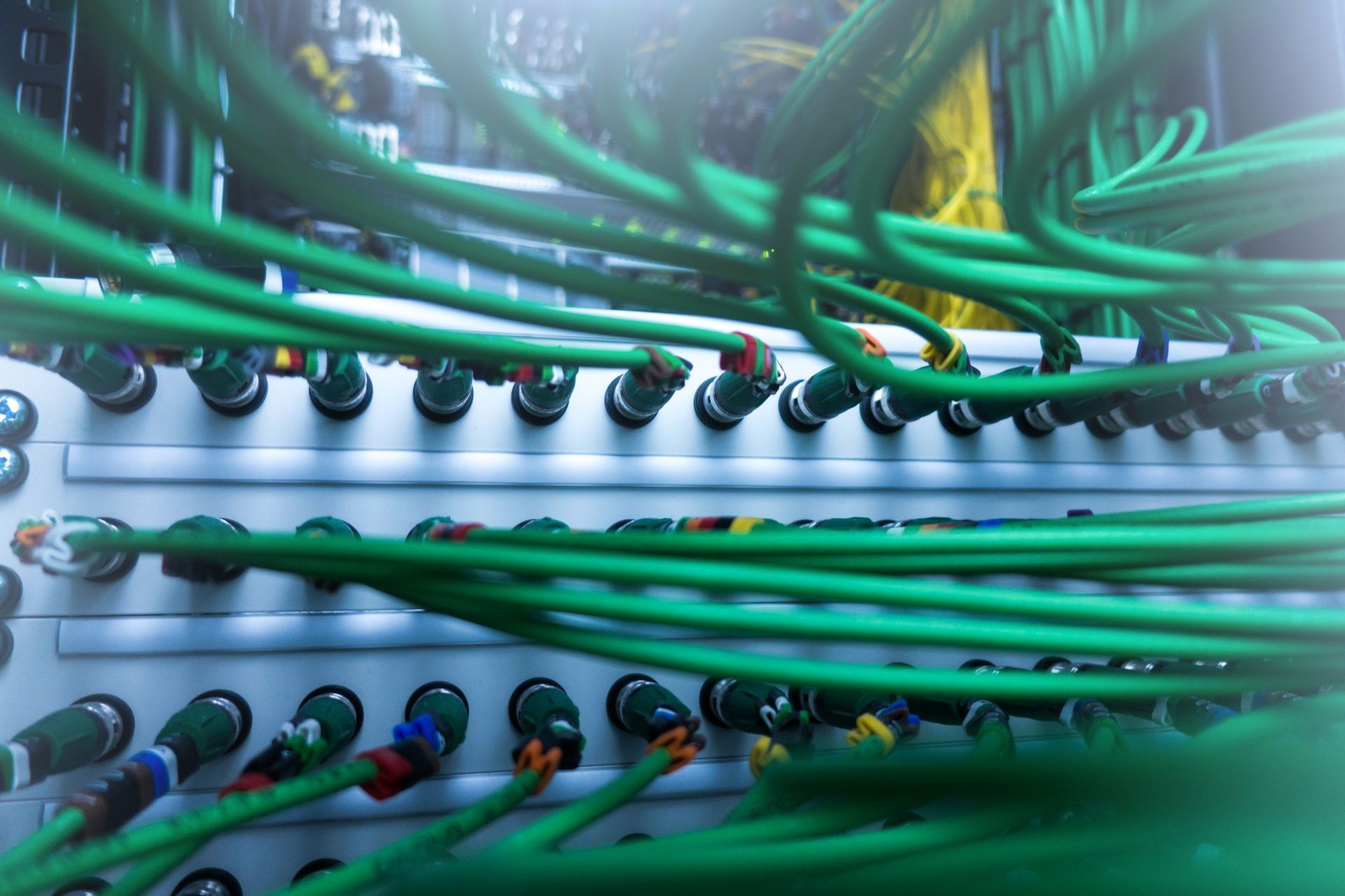 A bunch of green wires are connected to each other in a server room.