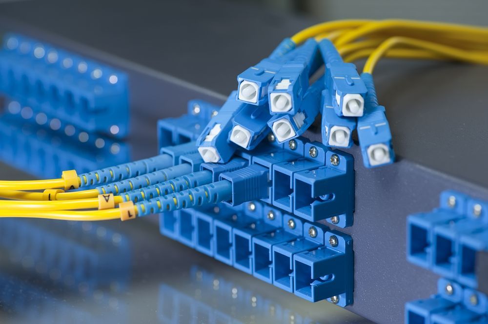 A bunch of blue and yellow optical fiber cables are connected to a rack.