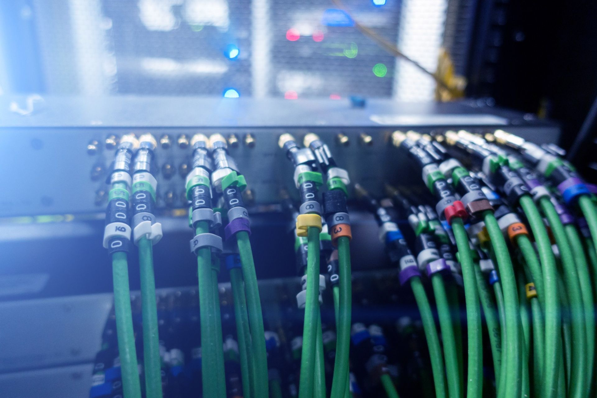 A bunch of green wires are connected to a server in a server room.