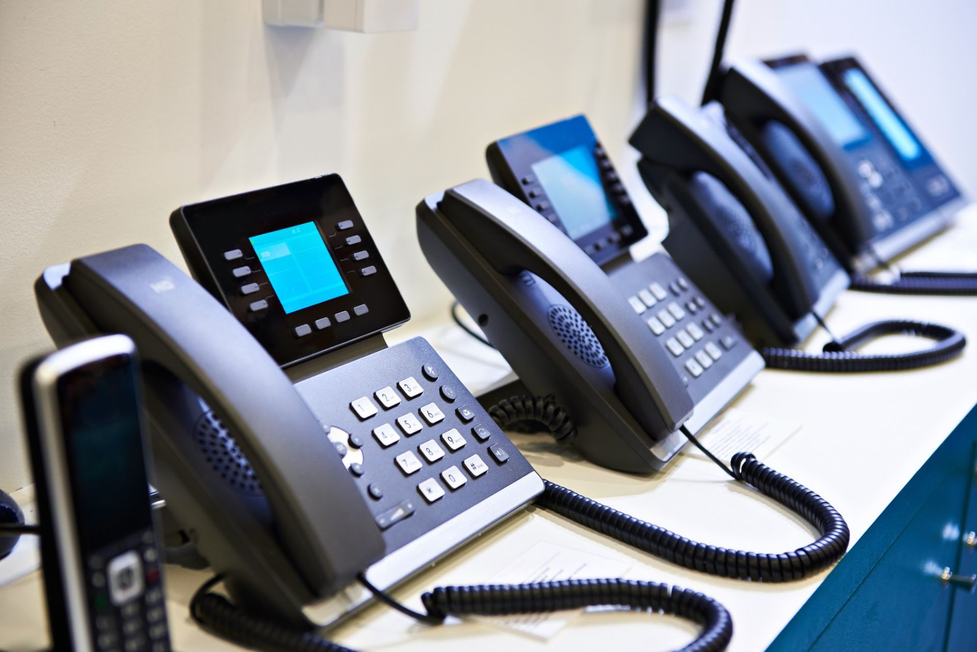 A row of telephones are lined up on a table.