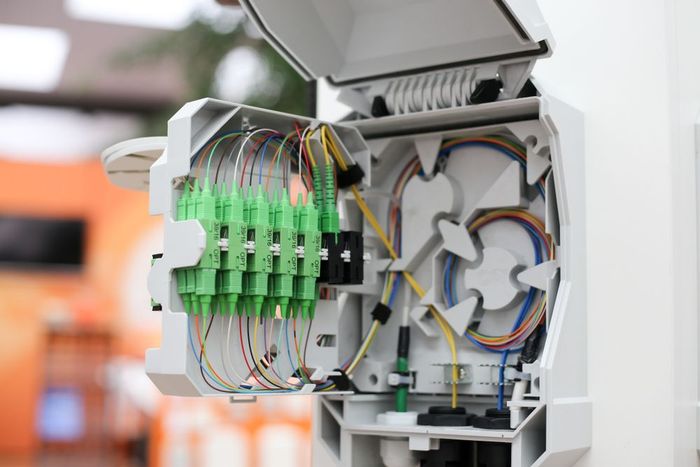 A close up of a fiber optic box with a lot of wires coming out of it.