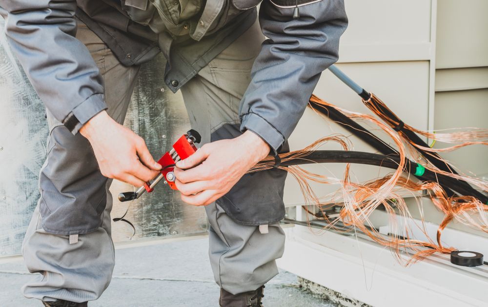 A man is cutting a wire with a pair of scissors.