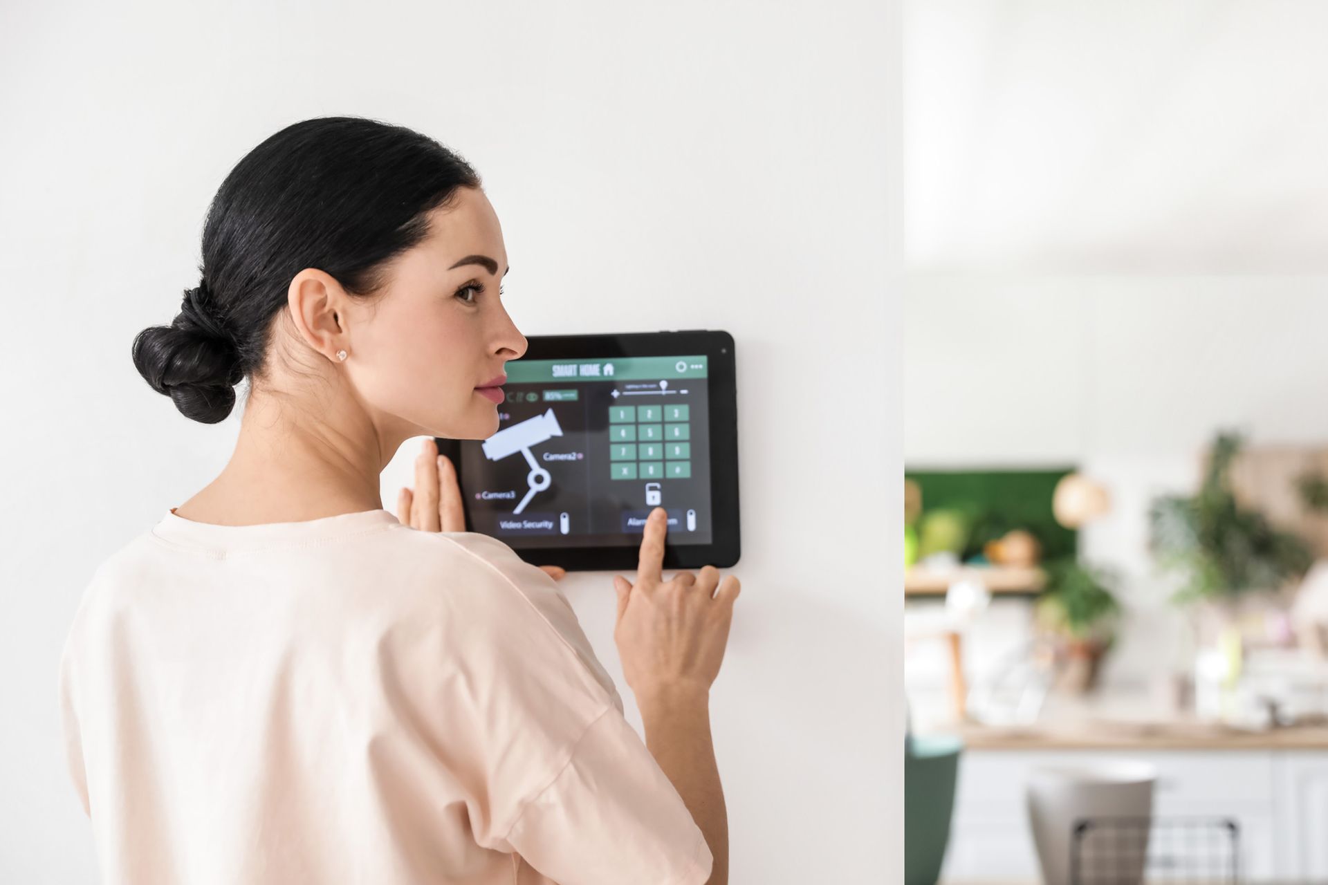 A woman is using a tablet to control her home security system.