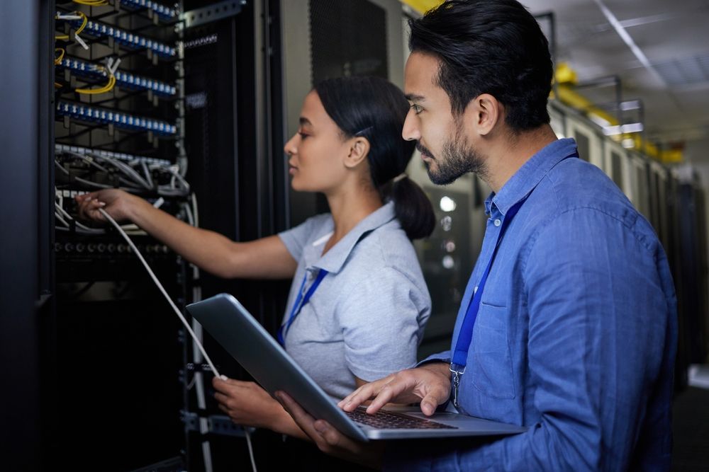 A man and a woman are working on a server in a data center.