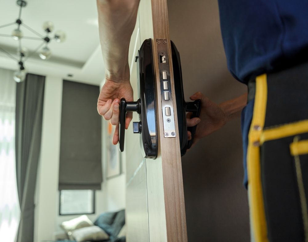 A man is installing a door lock in a living room.