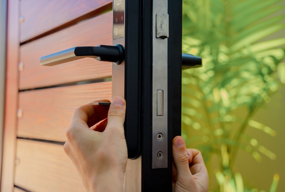 A person is installing a door lock on a wooden door.