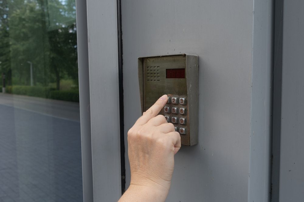 A person is pressing a keypad on a door.