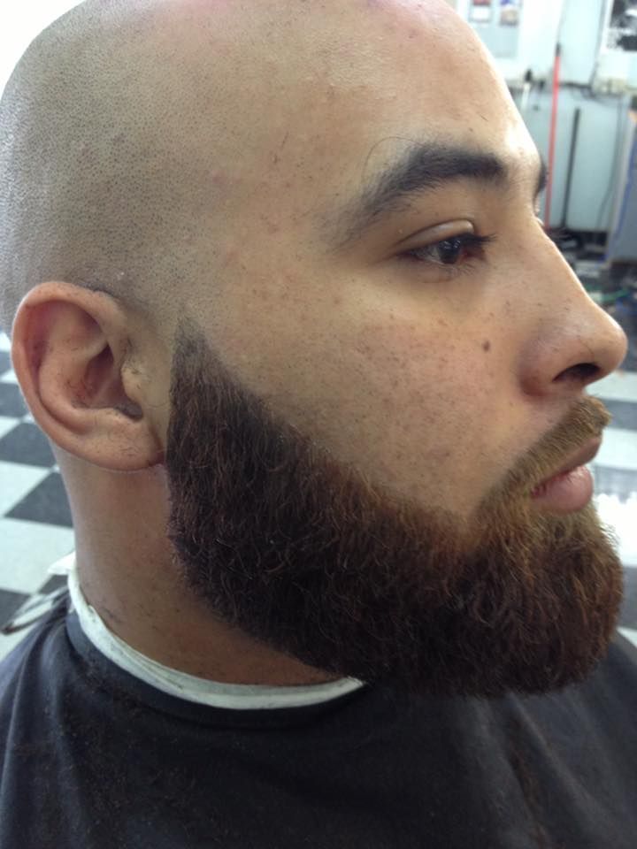 A man with a beard is getting his hair cut at a barber shop.
