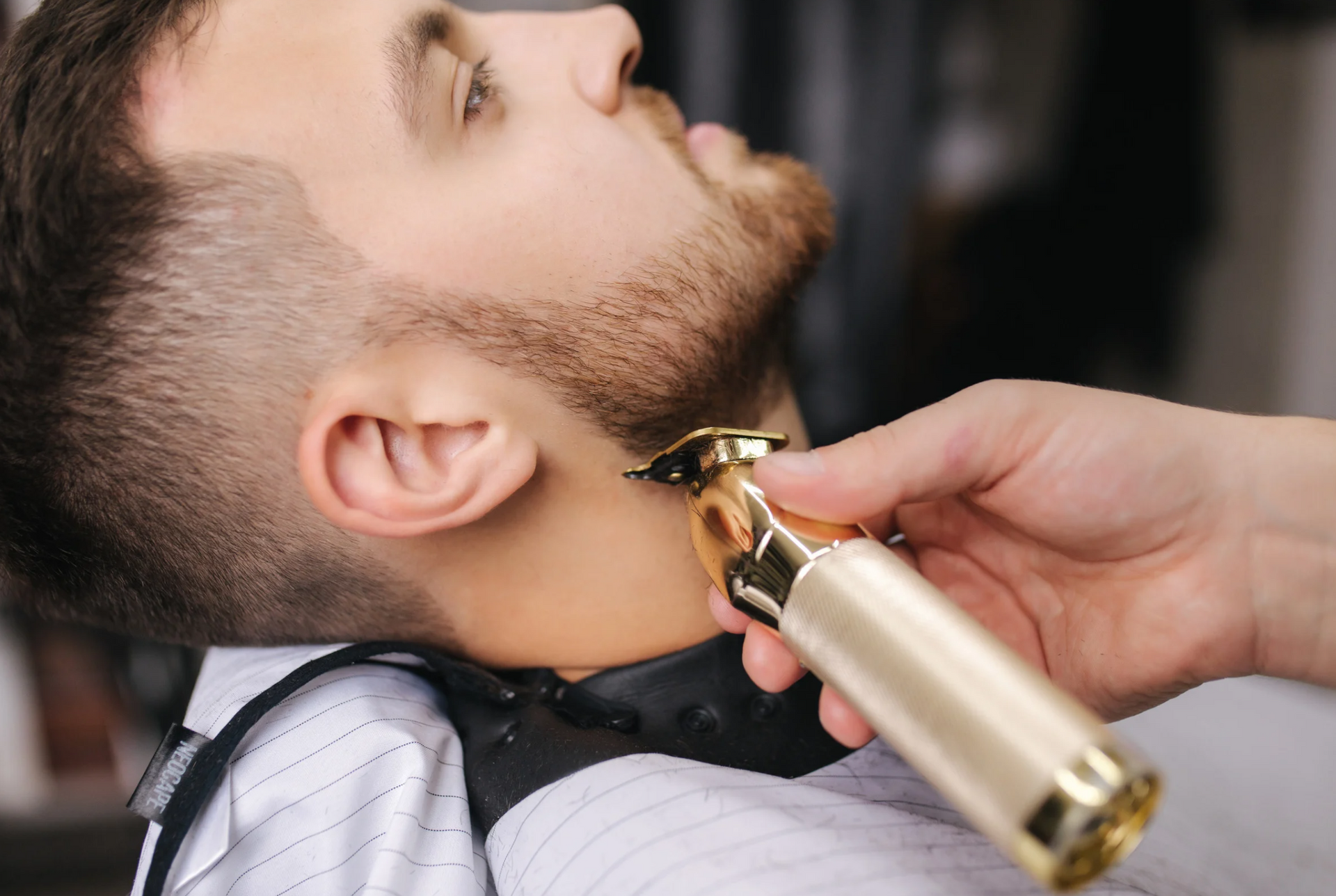 A man is getting his beard trimmed by a barber.