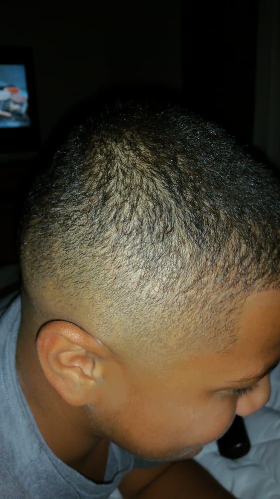 A young boy with a shaved head is sitting in front of a television.