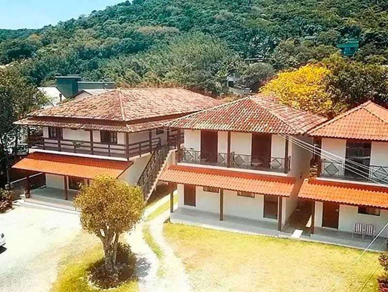 Edifícios com telhados de telha vermelha e paredes brancas, aninhados em uma exuberante encosta verdejante.