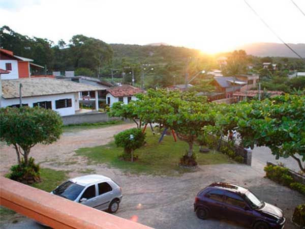 Pôr do sol sobre uma cidade com casas, árvores e carros estacionados.