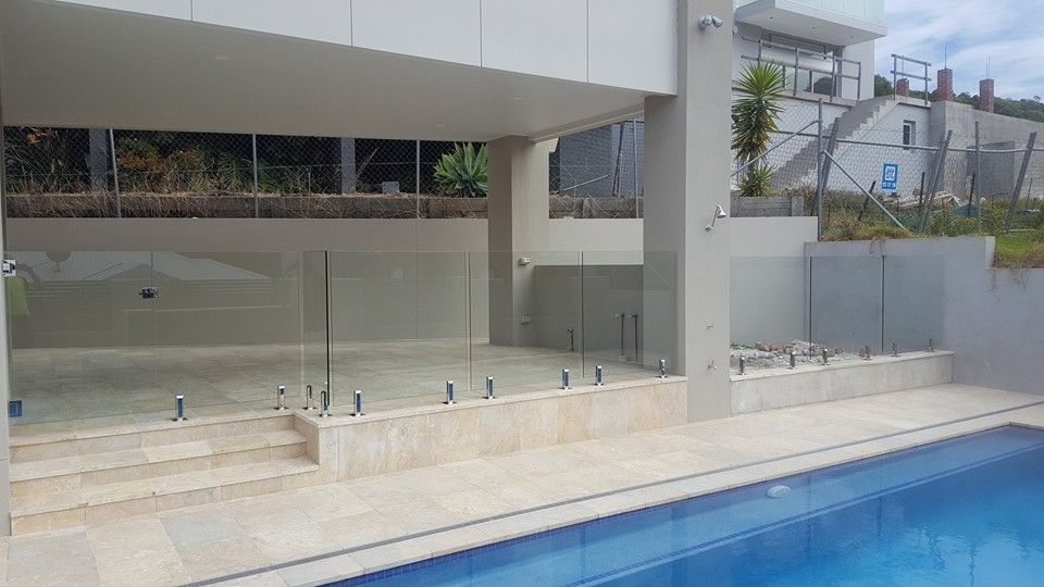 Poolside Area With Glass Fence, Tile, And Steps, Next To A Blue Swimming Pool — D & T Balustrade Systems In Unanderra, NSW
