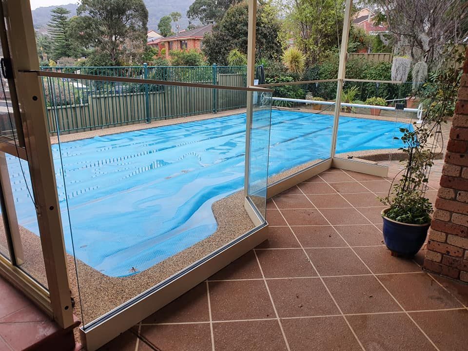 A Swimming Pool With a Blue Cover on It — D & T Balustrade Systems In Unanderra, NSW