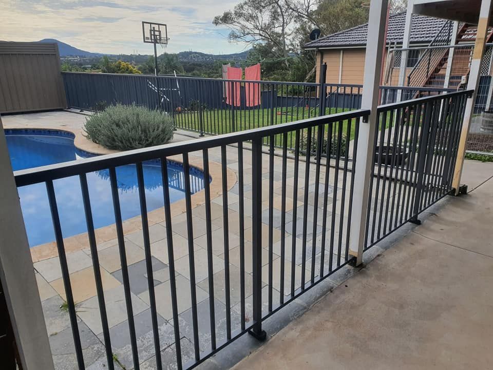 A Fence Surrounds a Swimming Pool With a Basketball Hoop in the Background — D & T Balustrade Systems In Unanderra, NSW