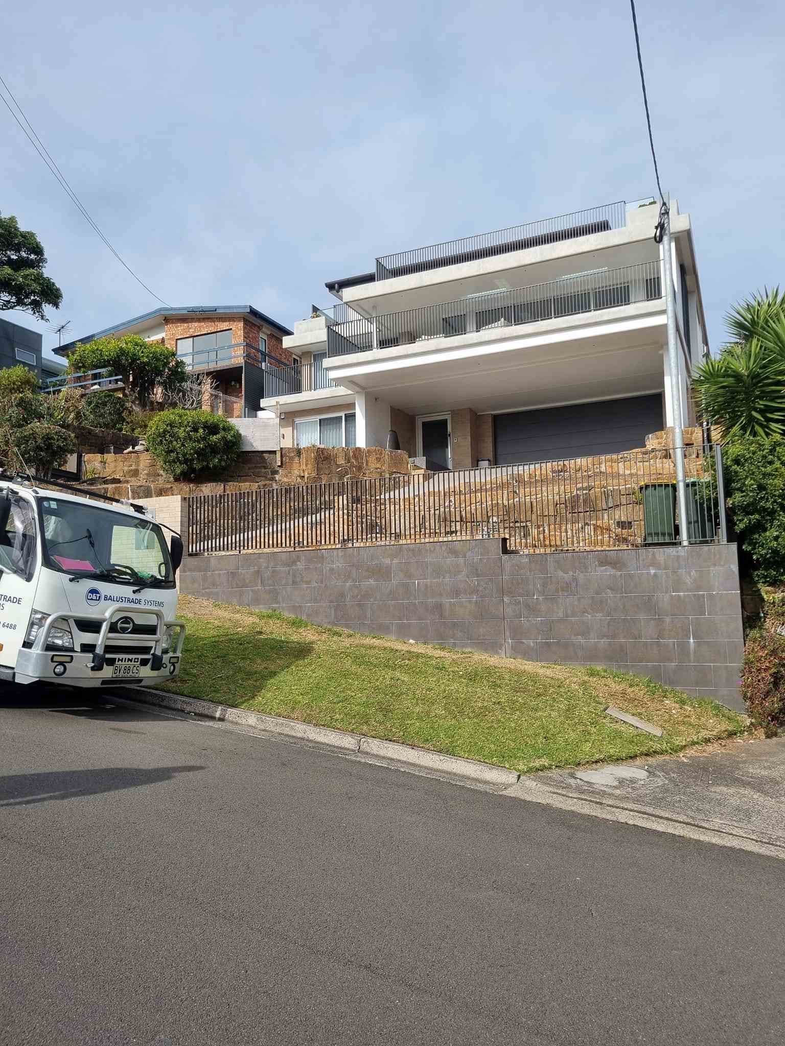 A White Truck is Parked in Front of a Large House on a Hill — D & T Balustrade Systems In Unanderra, NSW