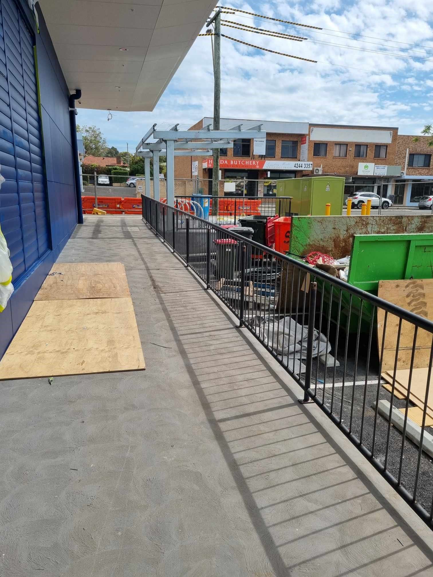 Ramp with black railings leading toward a street — D & T Balustrade Systems In Unanderra, NSW