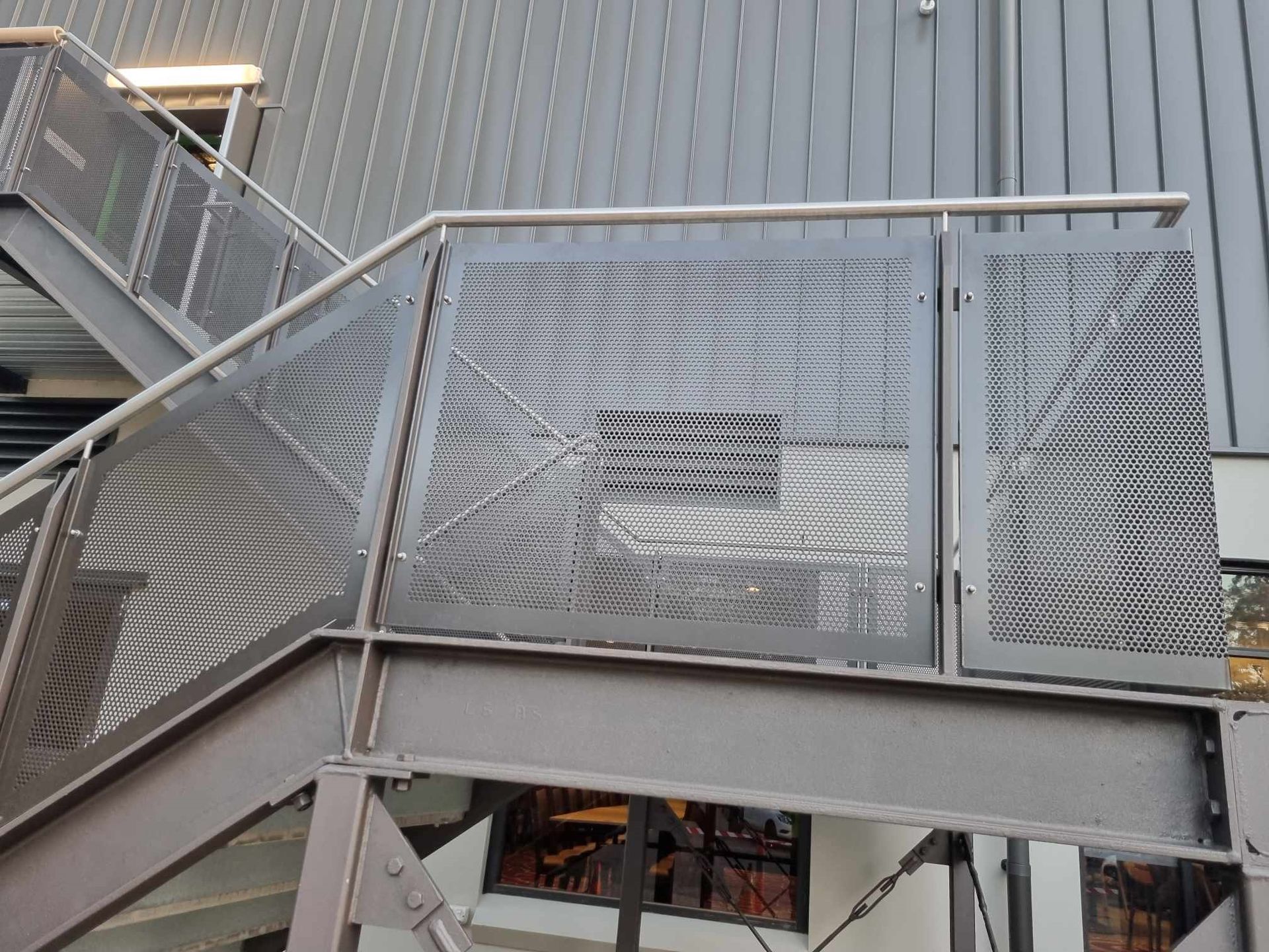 Metal staircase with perforated metal panels and handrails — D & T Balustrade Systems In Unanderra, NSW