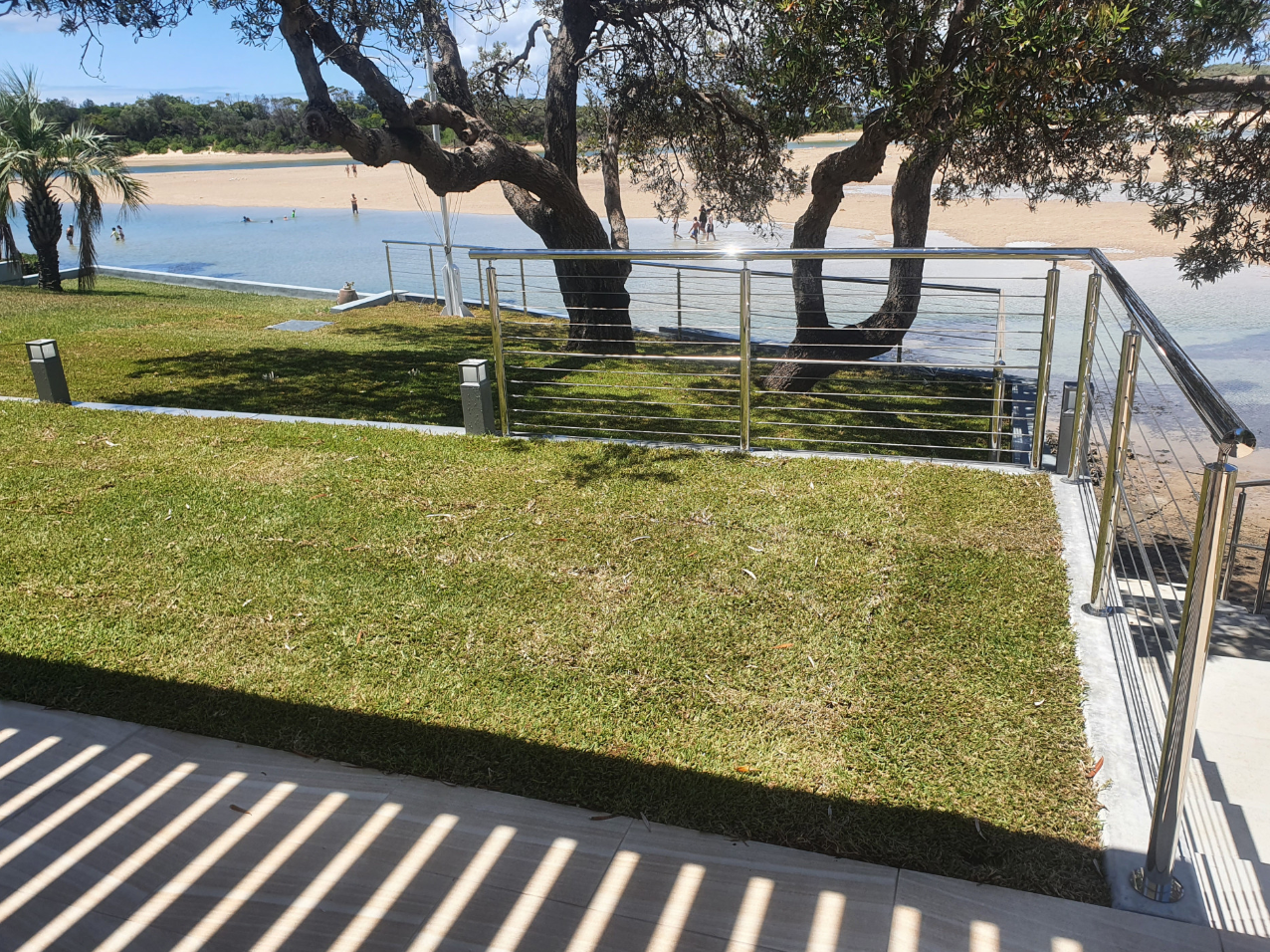 Grassy area with metal railings and a tree overlooking a body of water — D & T Balustrade Systems In Unanderra, NSW